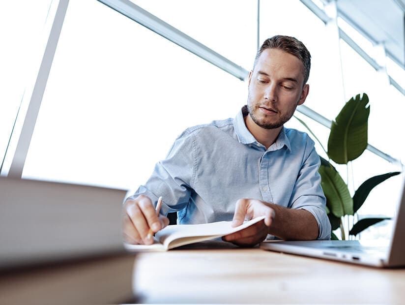 male accountant sitting at desk writing notes